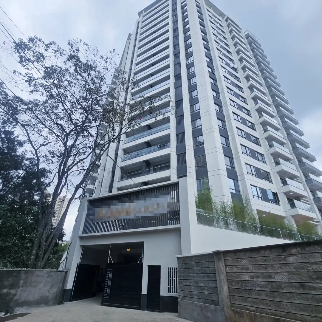 Modern high-rise residential building with entrance and compound wall