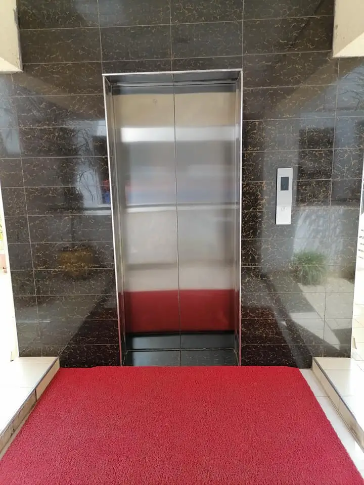 Modern elevator lobby with dark tile walls and red mat