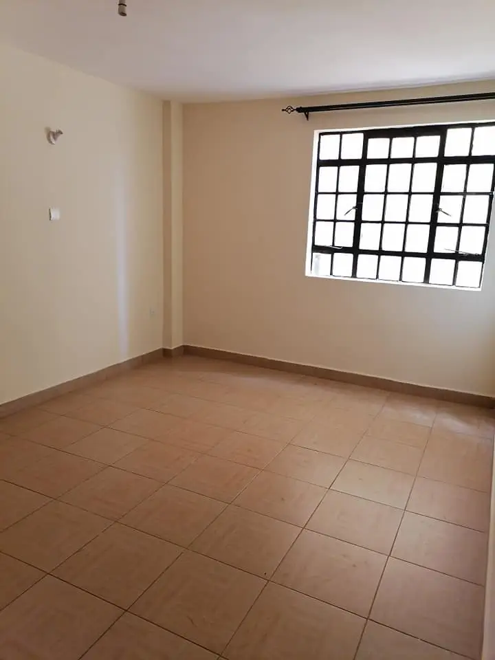 Empty bedroom with terracotta tile flooring and barred window