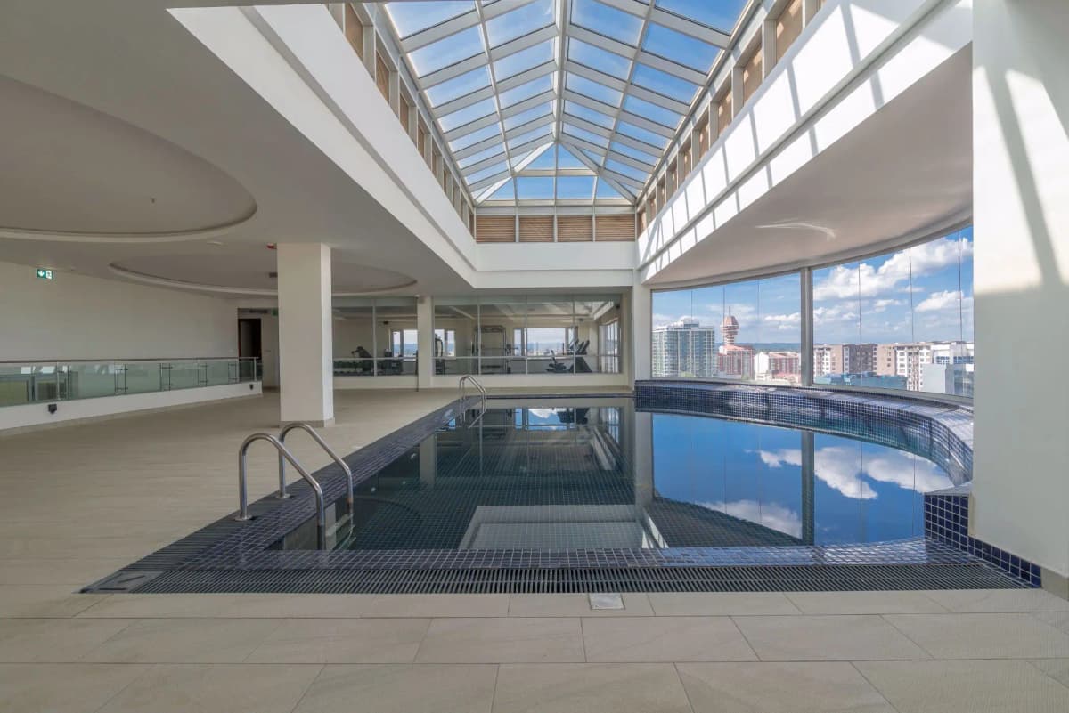 Indoor swimming pool with skylight roof and city views