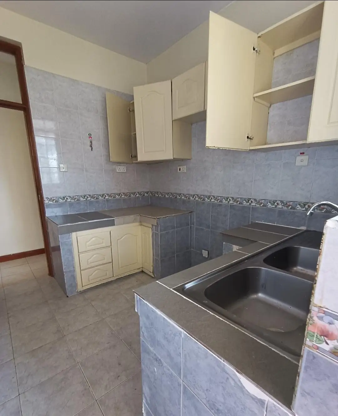 Compact kitchen with stainless steel sink and cream cabinets