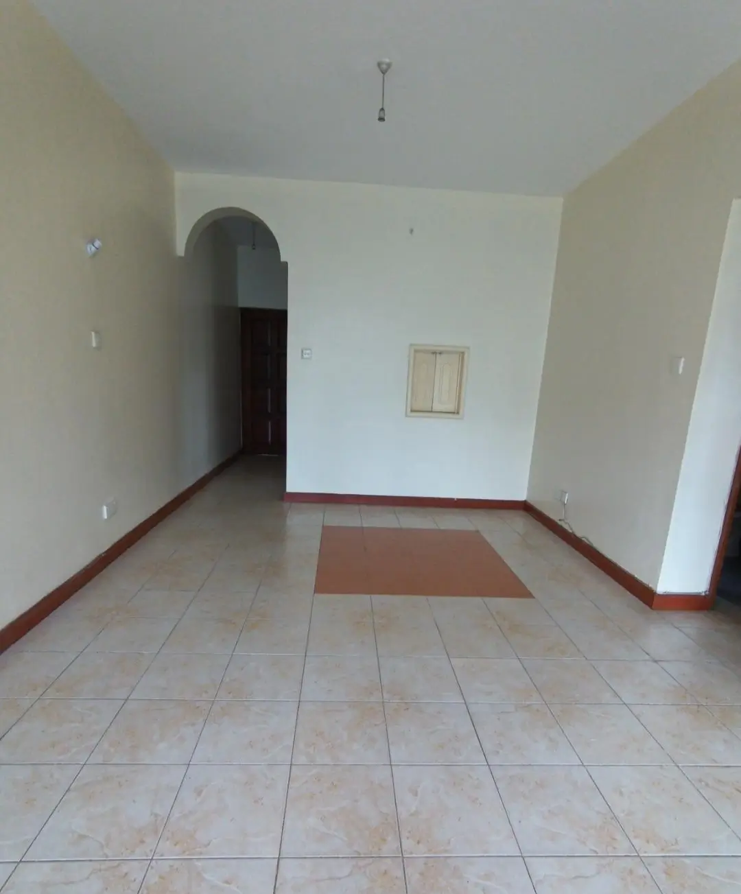 Empty living room with tiled floor and arched doorway