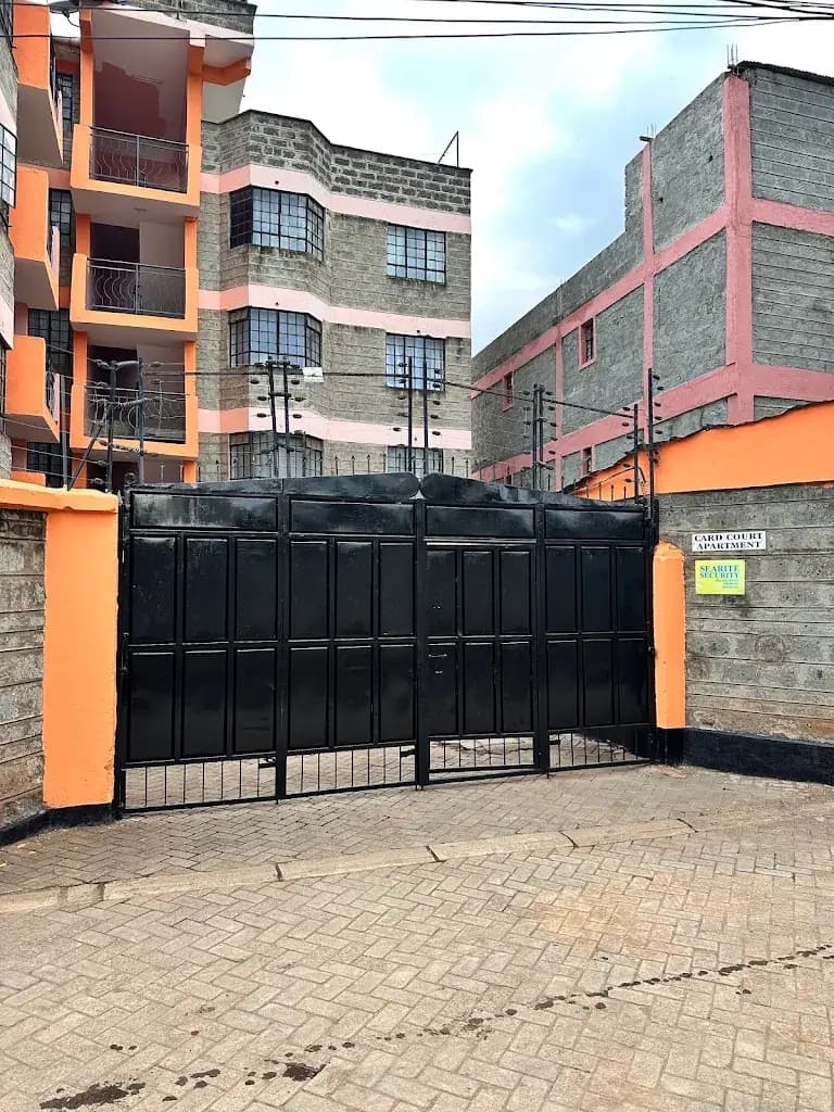 Compound entrance with black metal gates and orange pillars