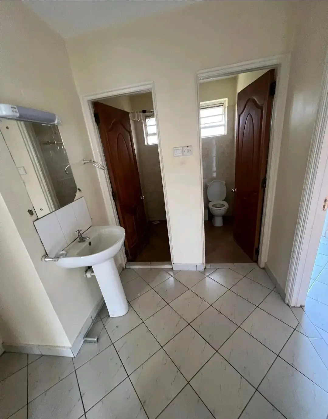 Bathroom with pedestal sink and multiple toilet cubicles