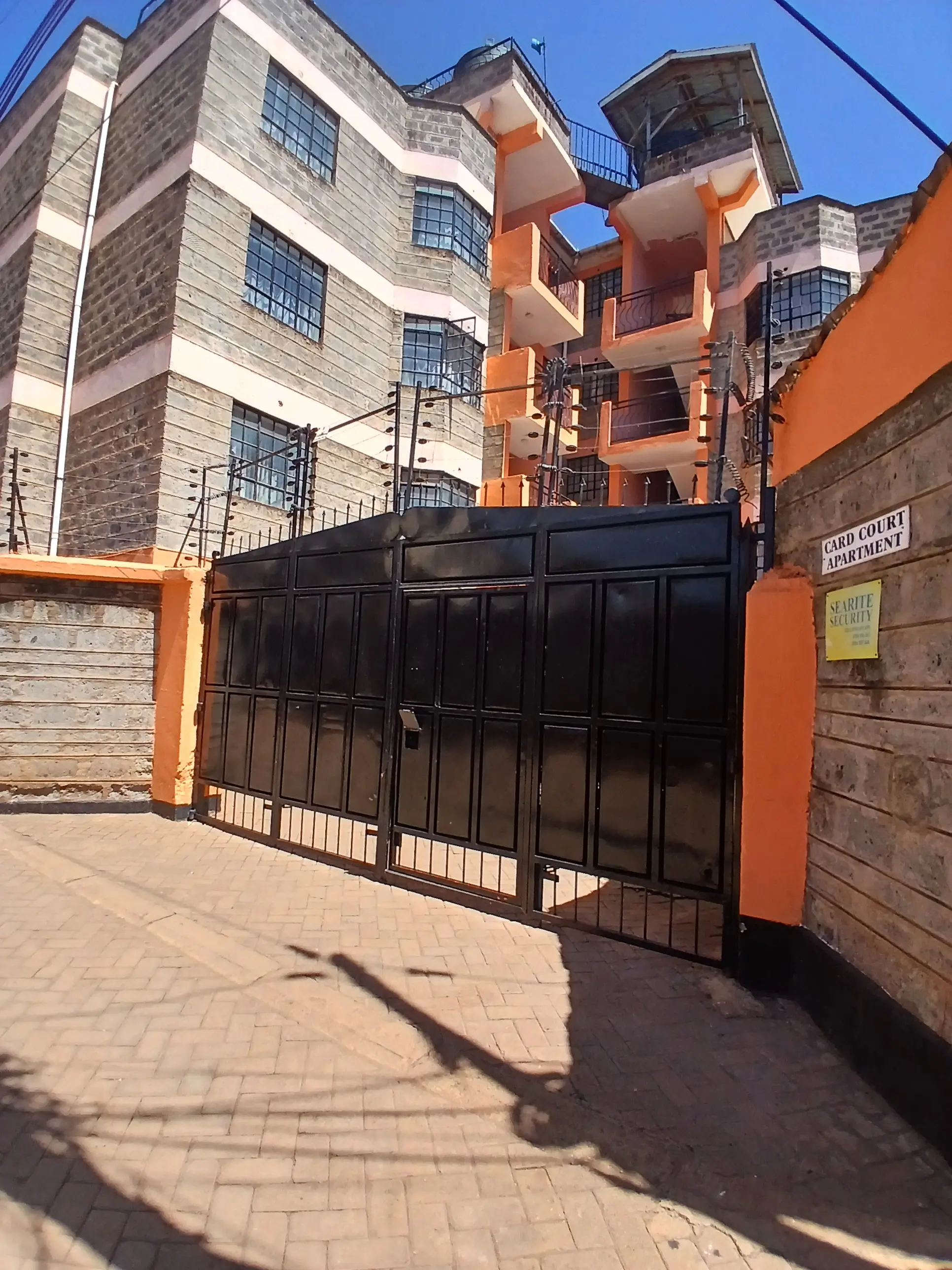 Multi-story residential building with orange and stone facade, black gate