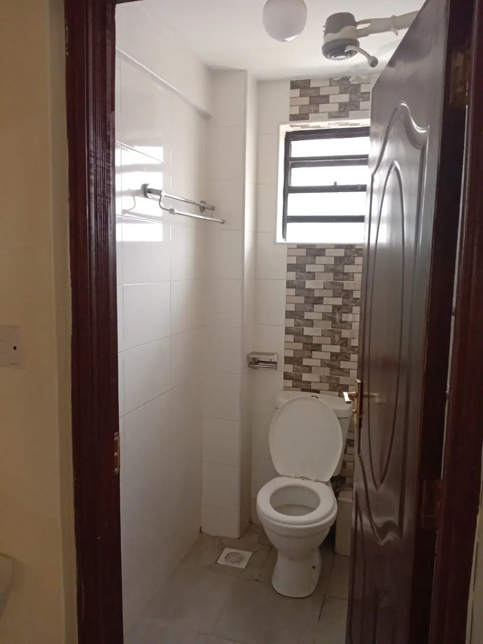 Compact bathroom with toilet, shower enclosure, tiled walls