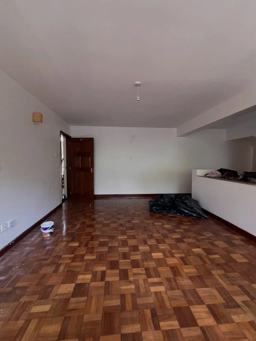 Spacious open living area with parquet flooring, minimal furnishings