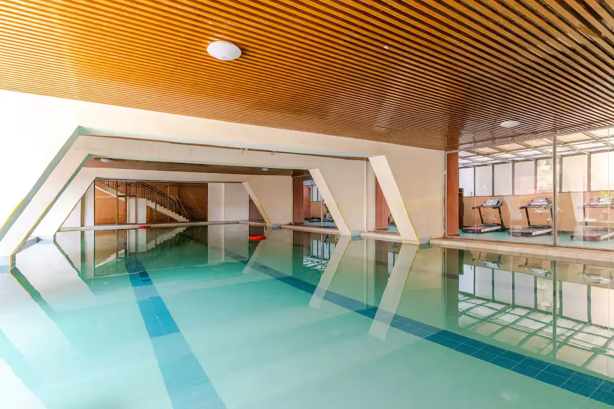 Indoor swimming pool with lane markings and modern wooden ceiling