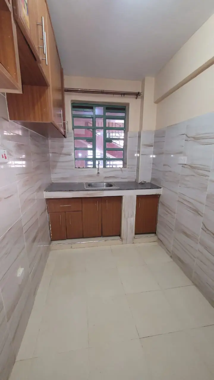 Compact kitchen with wooden cabinetry and tiled backsplash