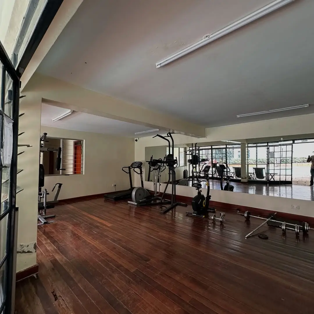 Spacious gym with cardio equipment and wooden flooring
