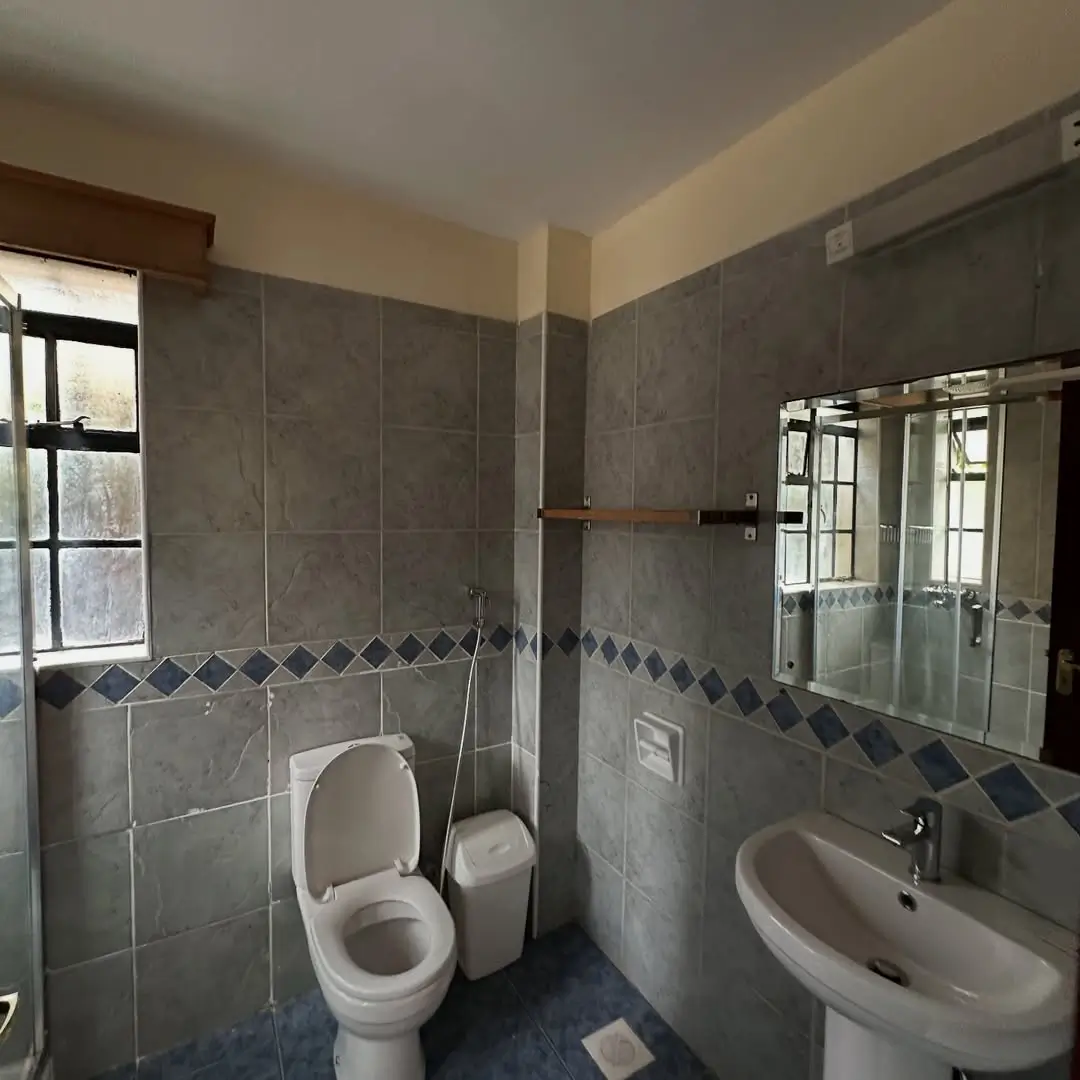 Spacious bathroom with toilet, sink, and tiled walls