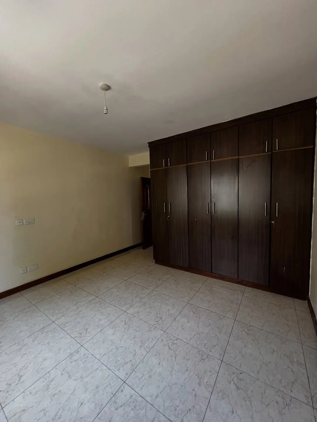 Spacious bedroom with built-in dark wooden wardrobes