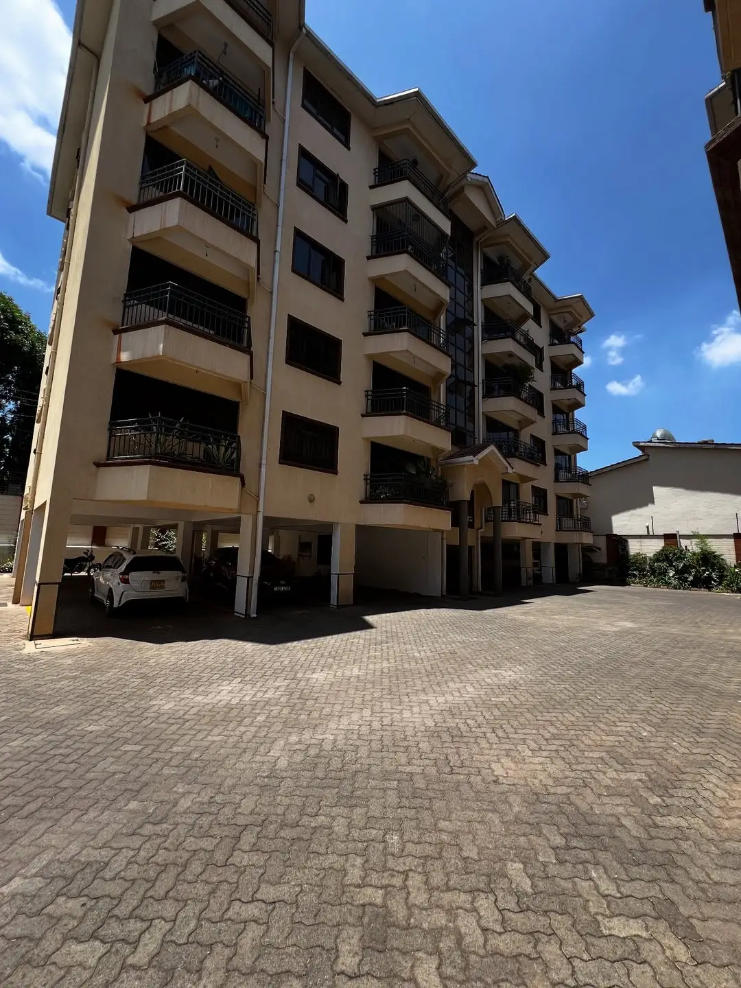 Modern multi-story residential building with ground-level parking bays