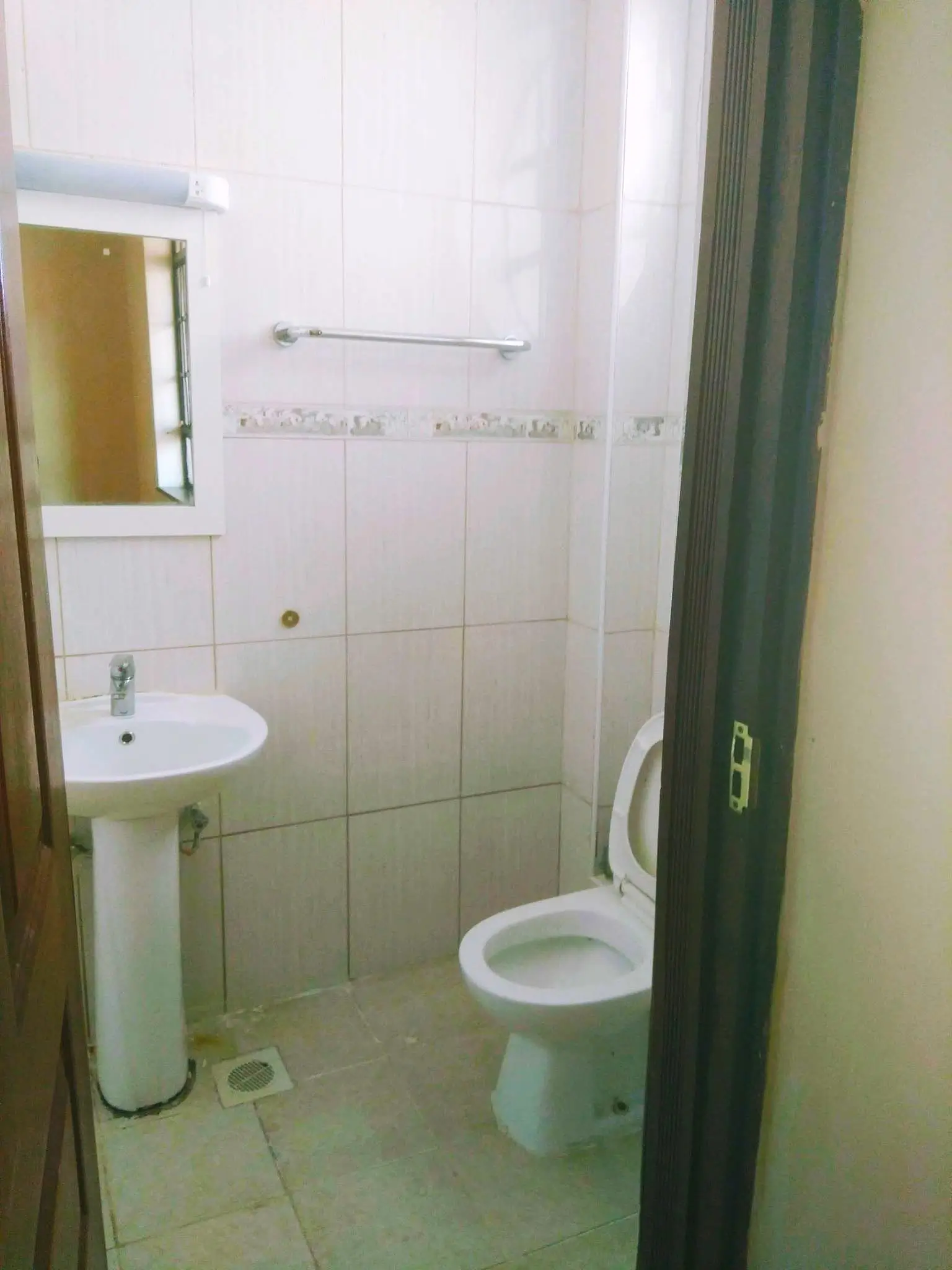 Clean bathroom with pedestal sink, toilet, and tiled walls