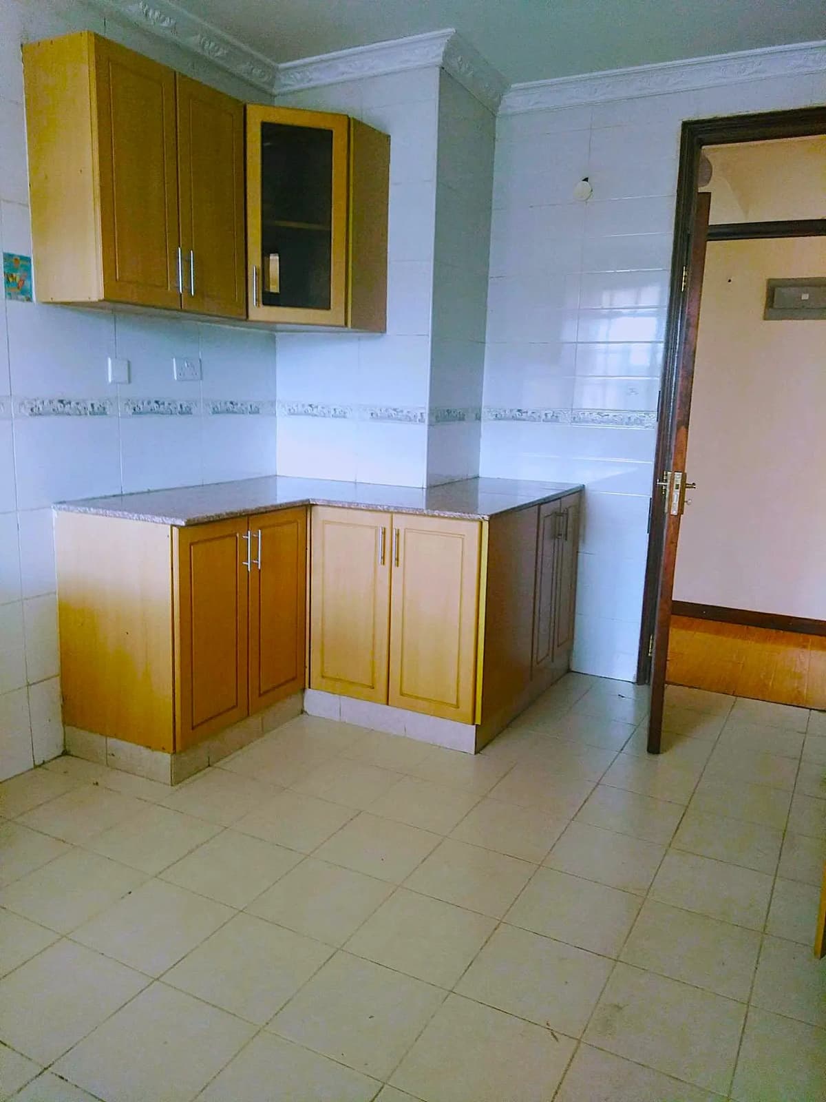 L-shaped kitchen with yellow cabinetry and tiled flooring