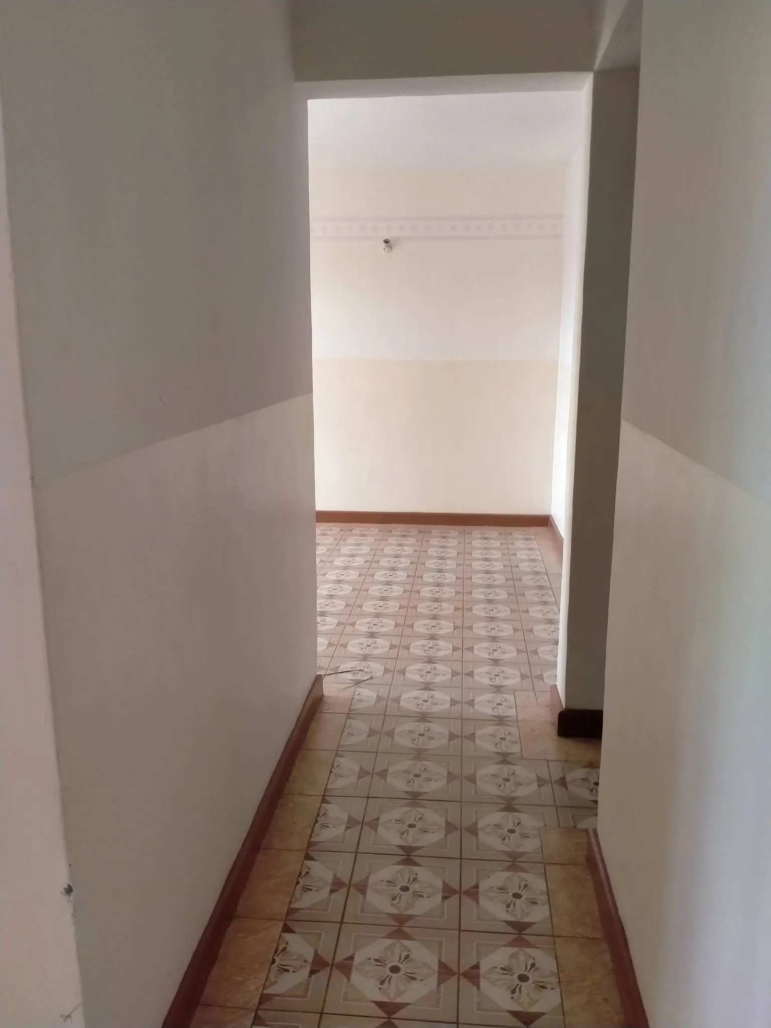Narrow hallway with patterned tile flooring and white walls