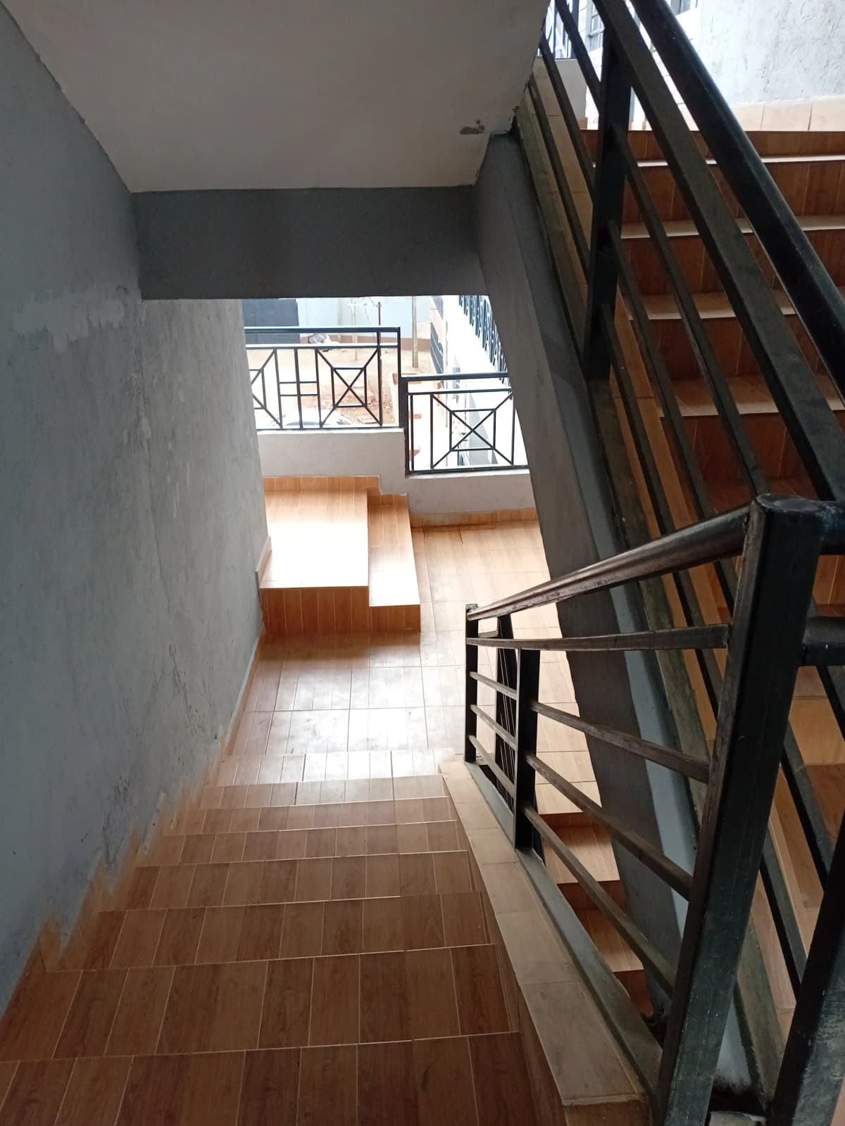 Stairwell landing with terracotta tiles and metal railings