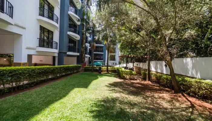 Manicured compound lawn with mature trees and hedges