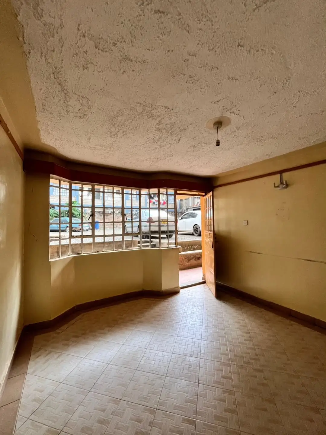 Spacious living room with barred windows and terracotta tile flooring