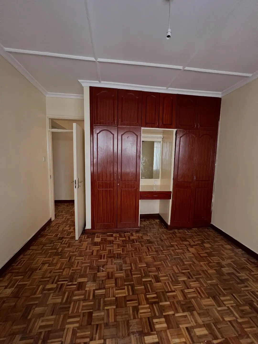 Spacious bedroom with built-in red wardrobe and parquet flooring