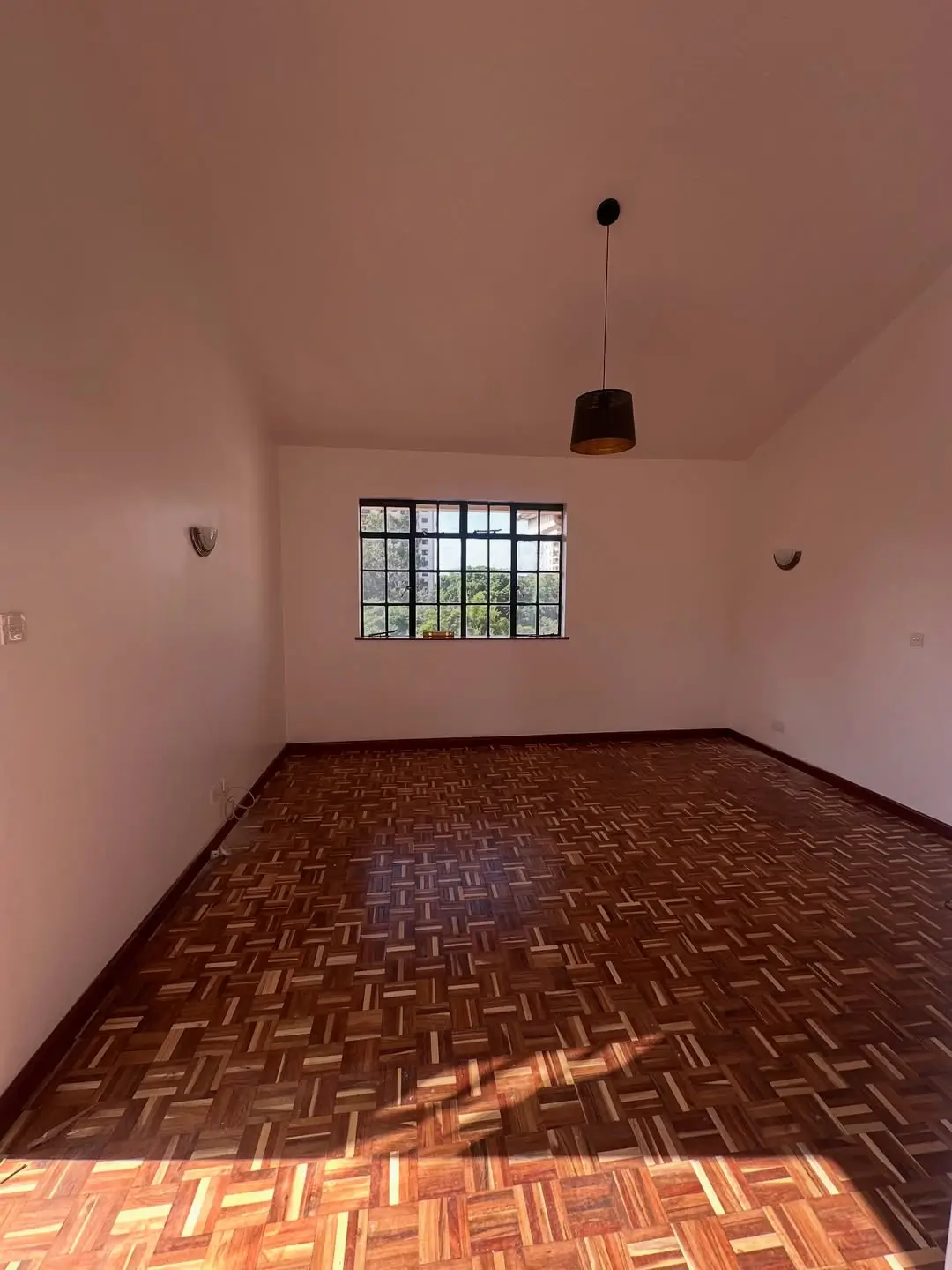 Unfurnished bedroom with herringbone wooden flooring and natural light