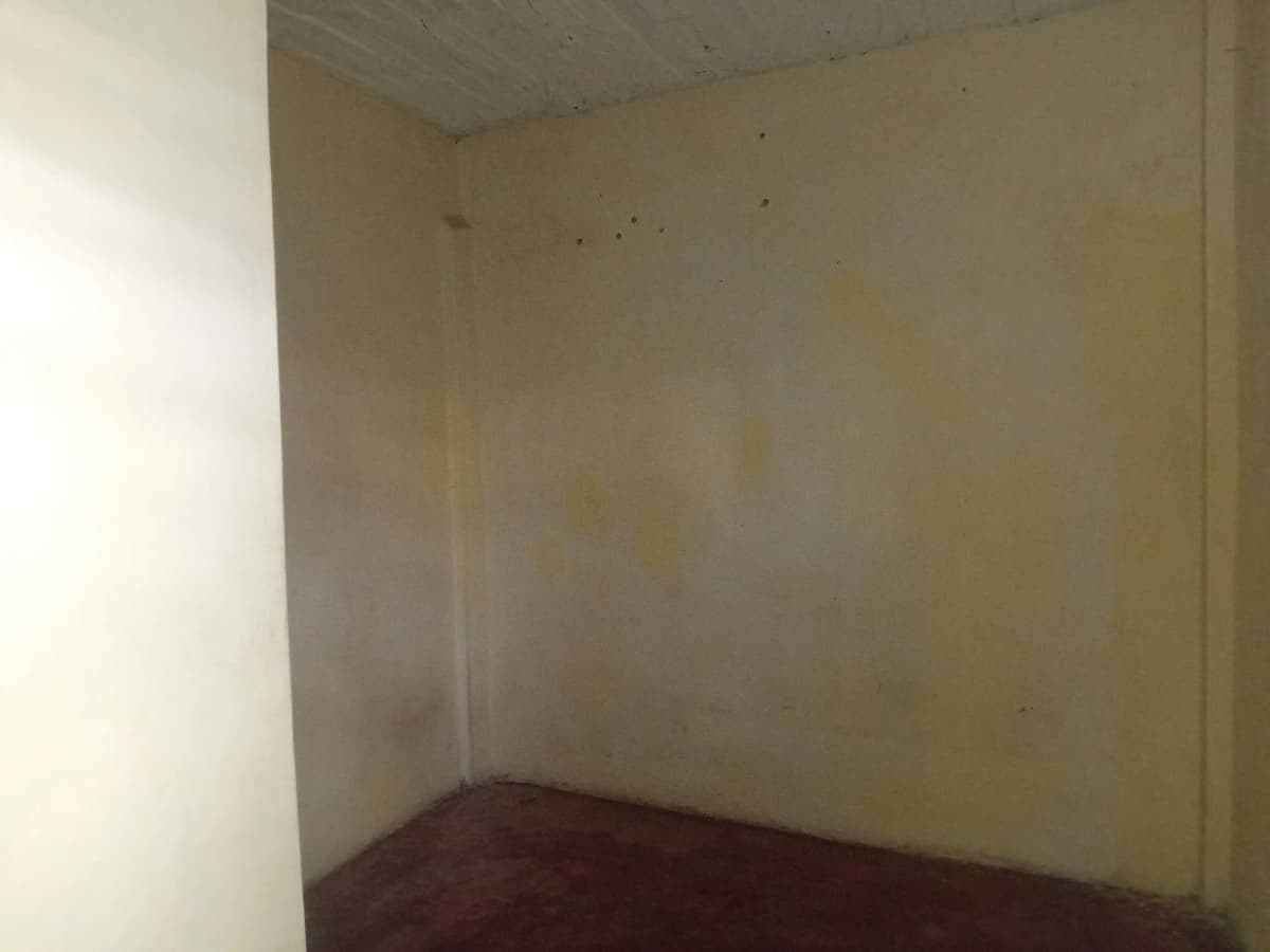 Empty bedroom with dark wooden floor and plain walls