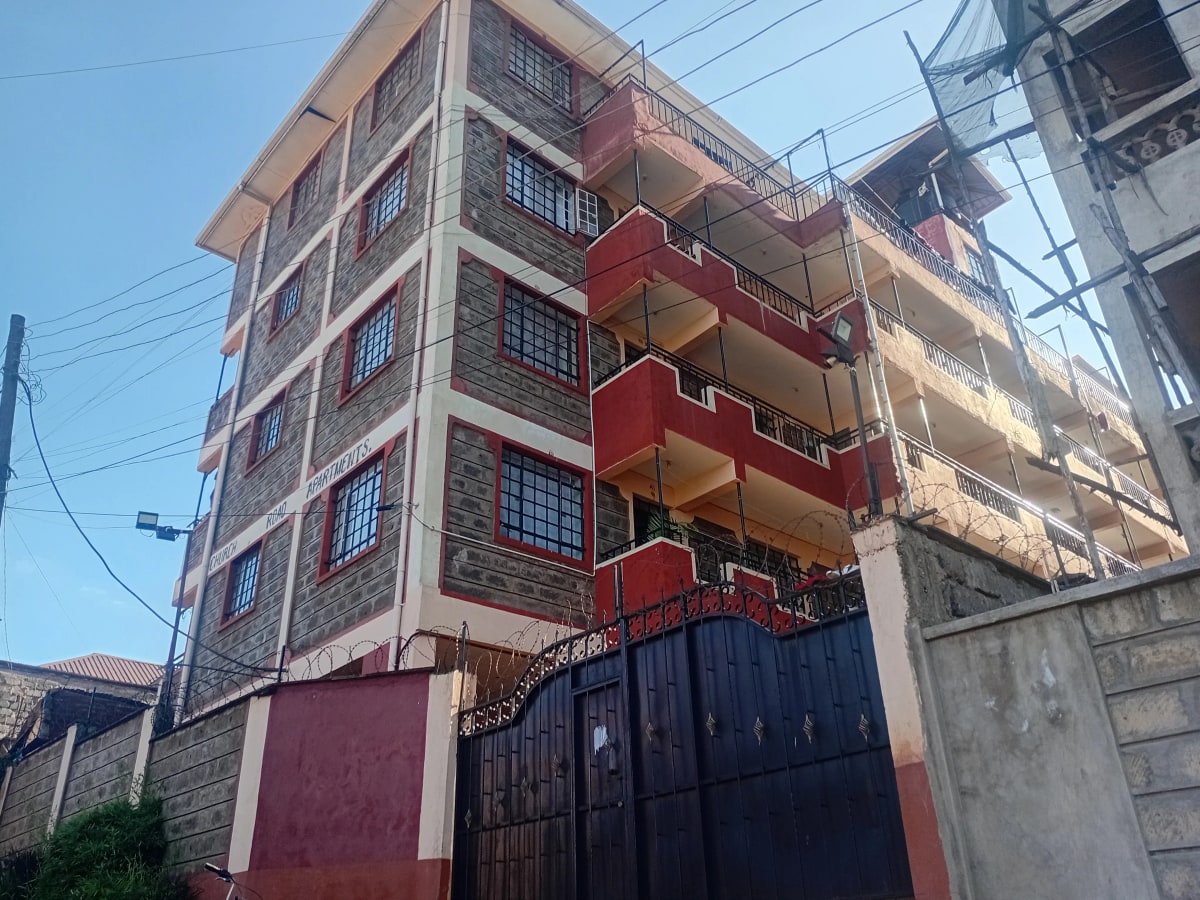 Multi-story residential building with red balconies and metal gate