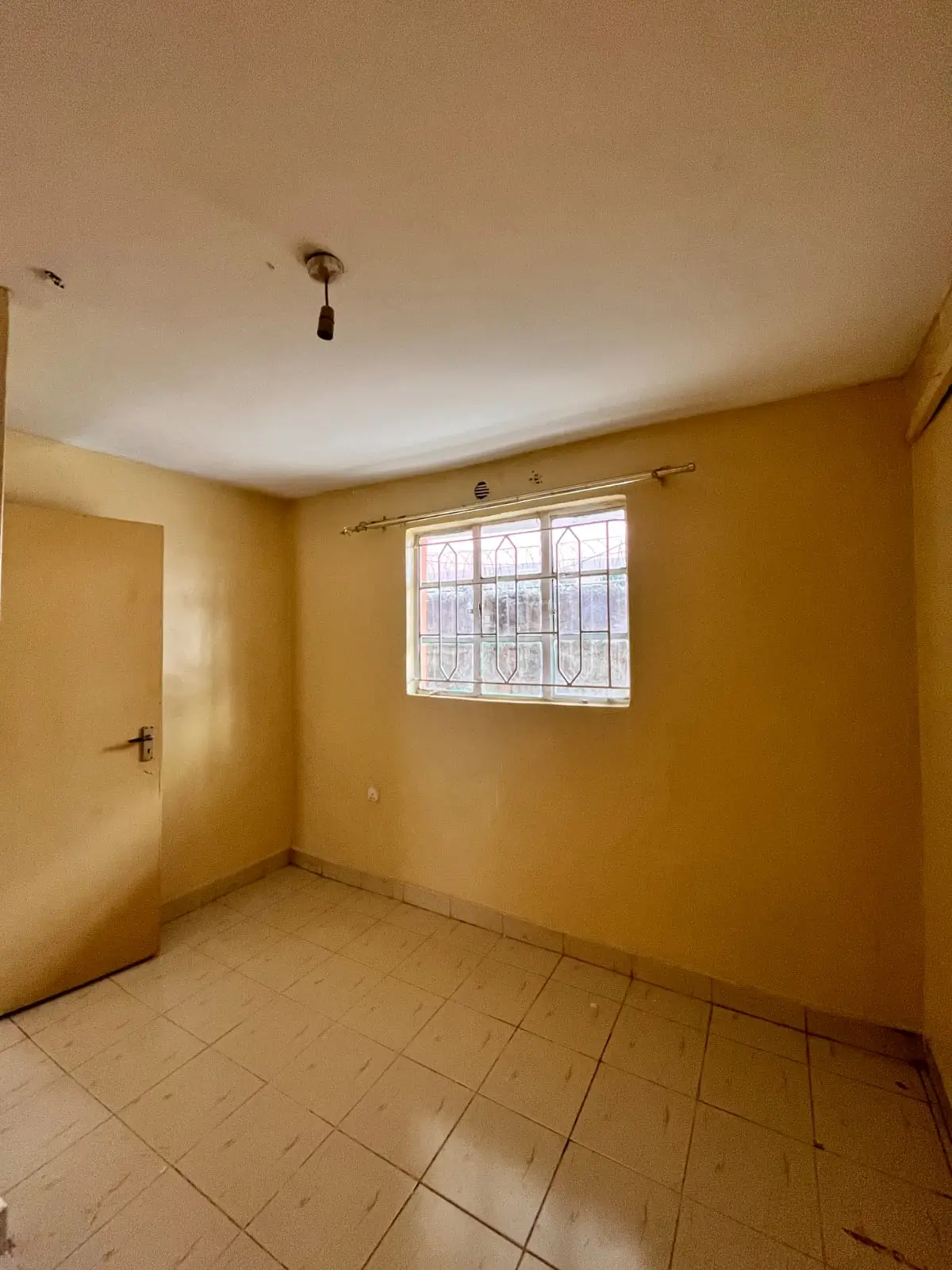 Empty bedroom with yellow walls and barred window