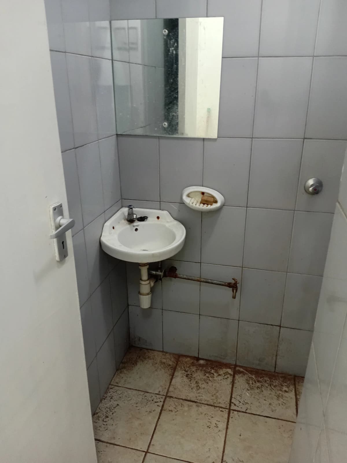 Basic bathroom with pedestal sink, mirror, and tiled walls