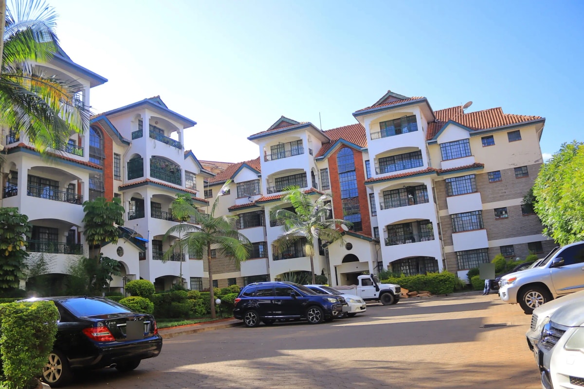 Multi-story residential compound with manicured gardens and parking