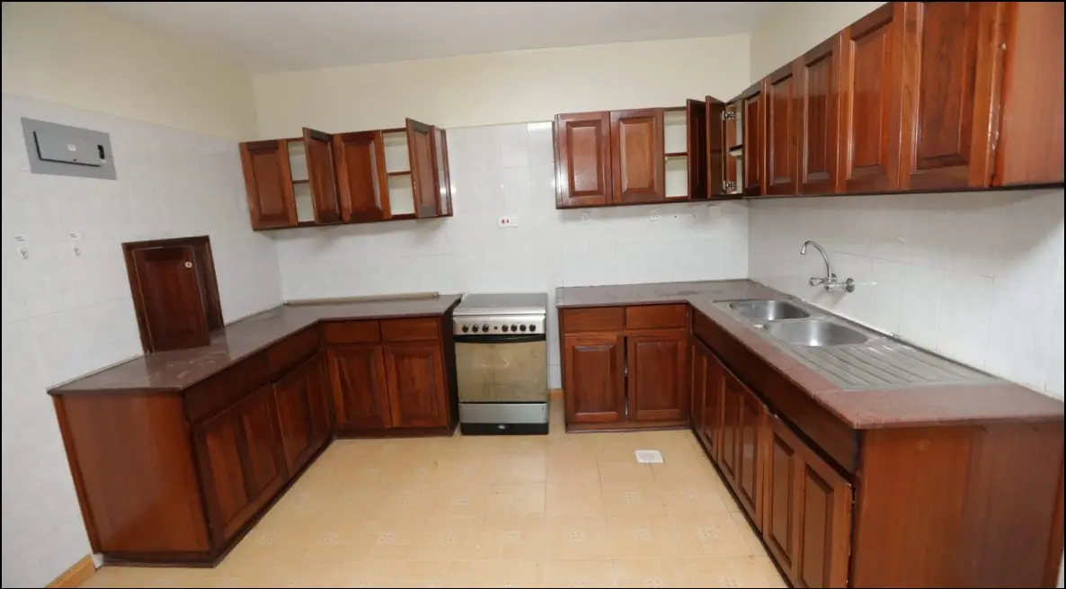 L-shaped kitchen with wooden cabinets and stainless steel stove