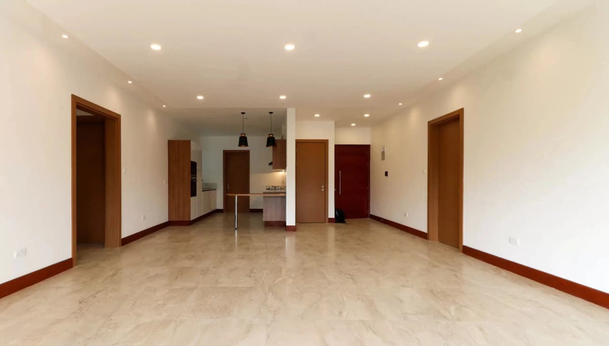 Spacious open-plan living area with kitchen visible in background