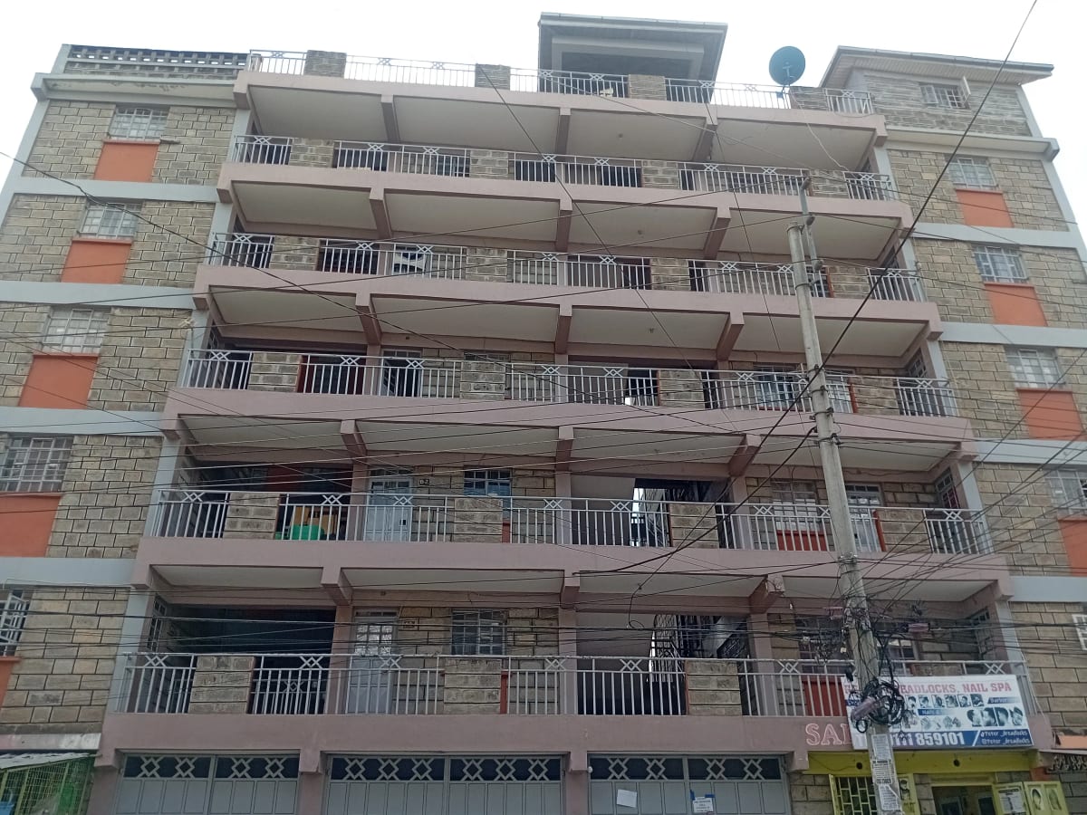 Multi-story residential building facade with balconies and ground-floor retail