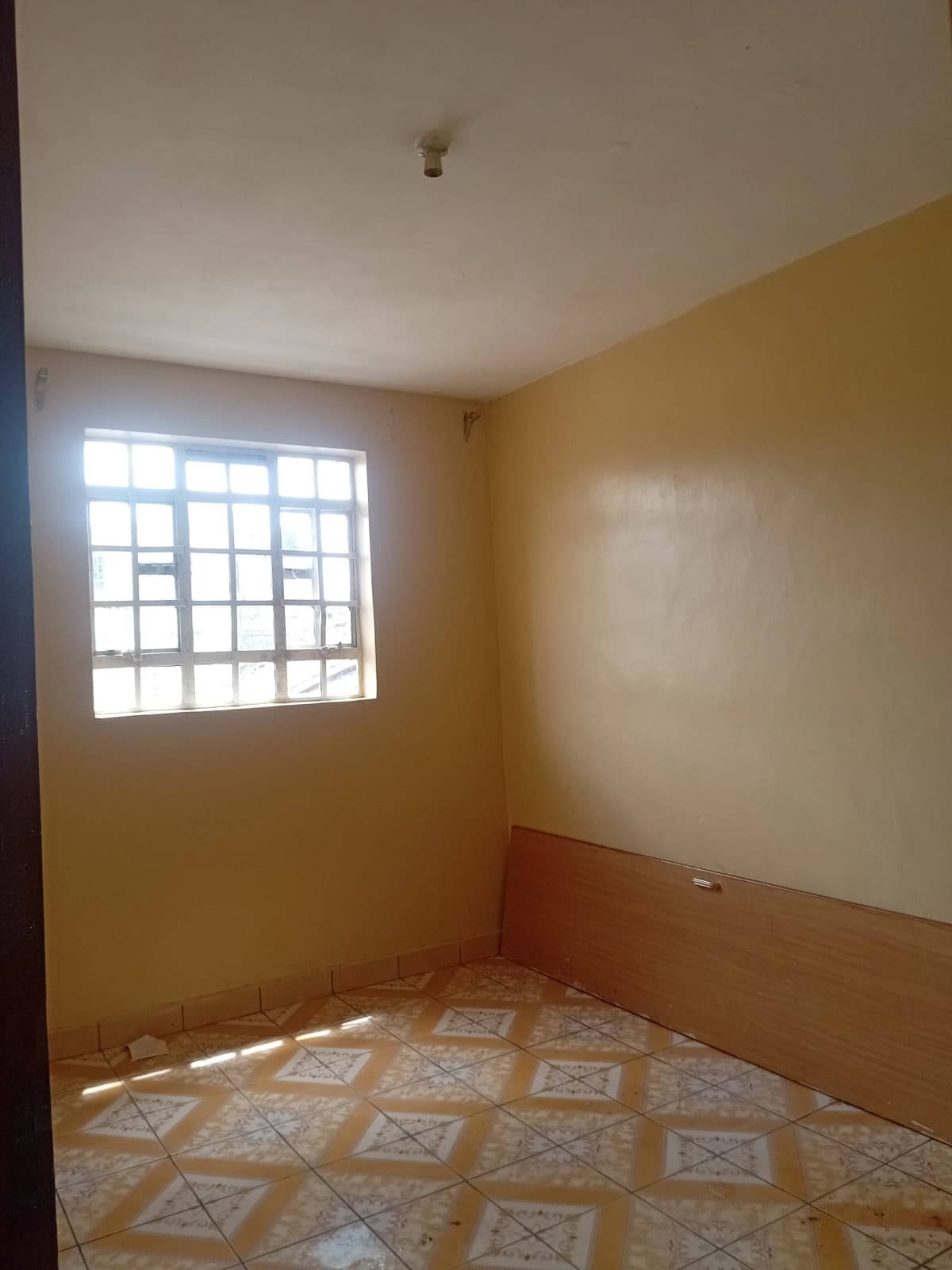 Empty bedroom with geometric tile floor and barred window