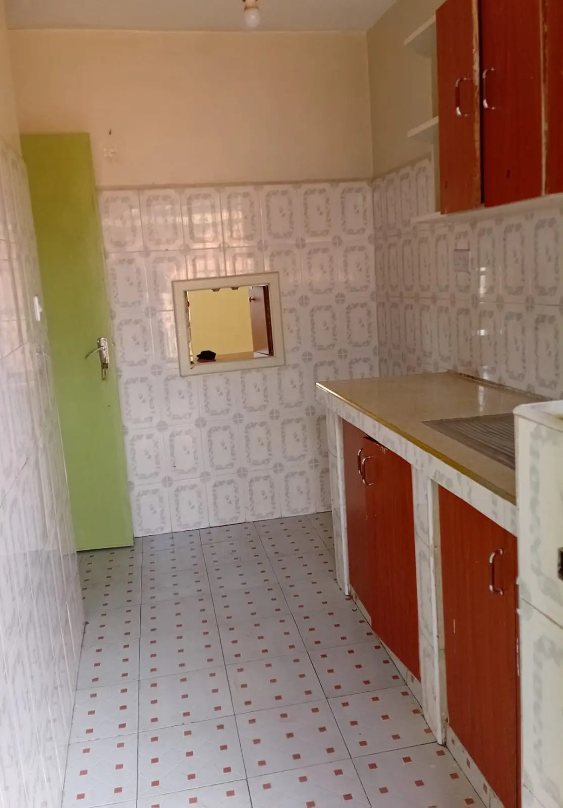 Compact kitchen with red cabinets and geometric tile flooring