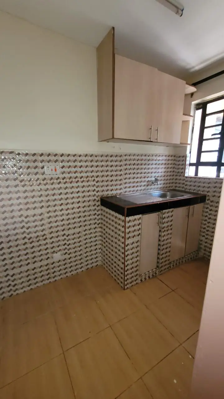 Compact kitchen with textured tile backsplash and black countertop