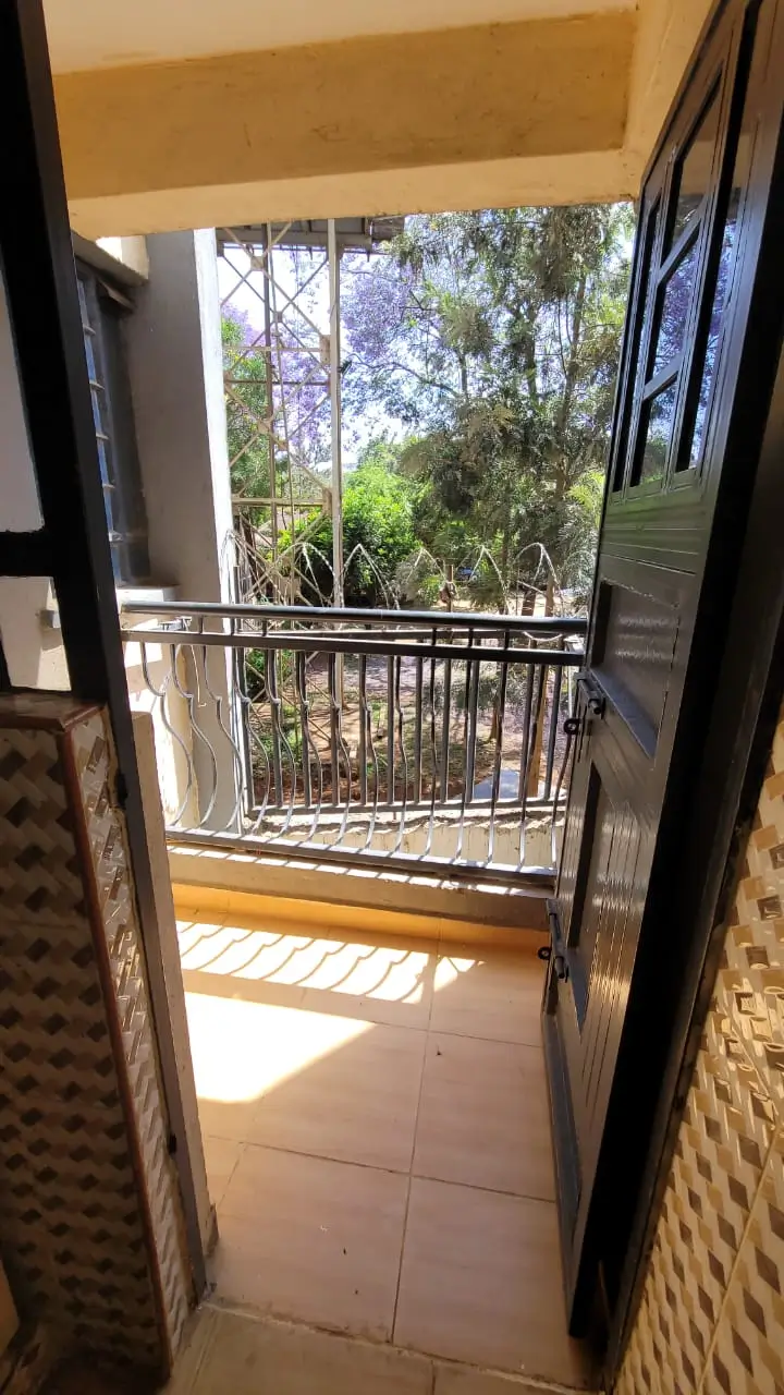 Balcony with railing overlooking lush green trees and garden
