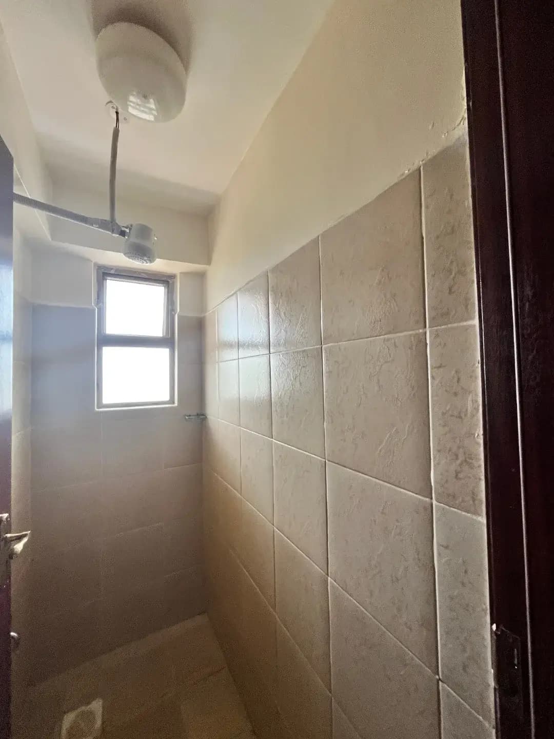 Narrow bathroom with tiled walls and natural light window