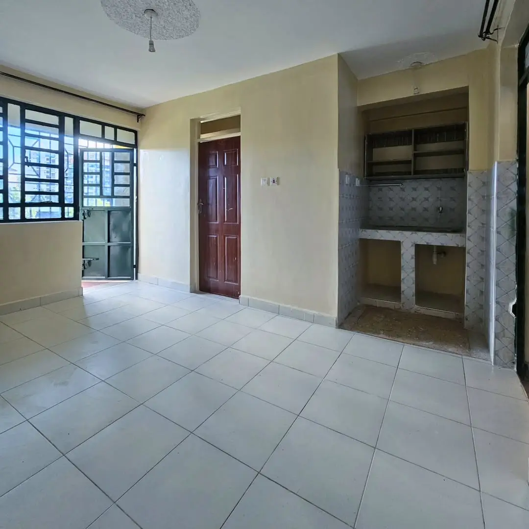 Open-plan living area with kitchen nook, cream walls, tiled floor