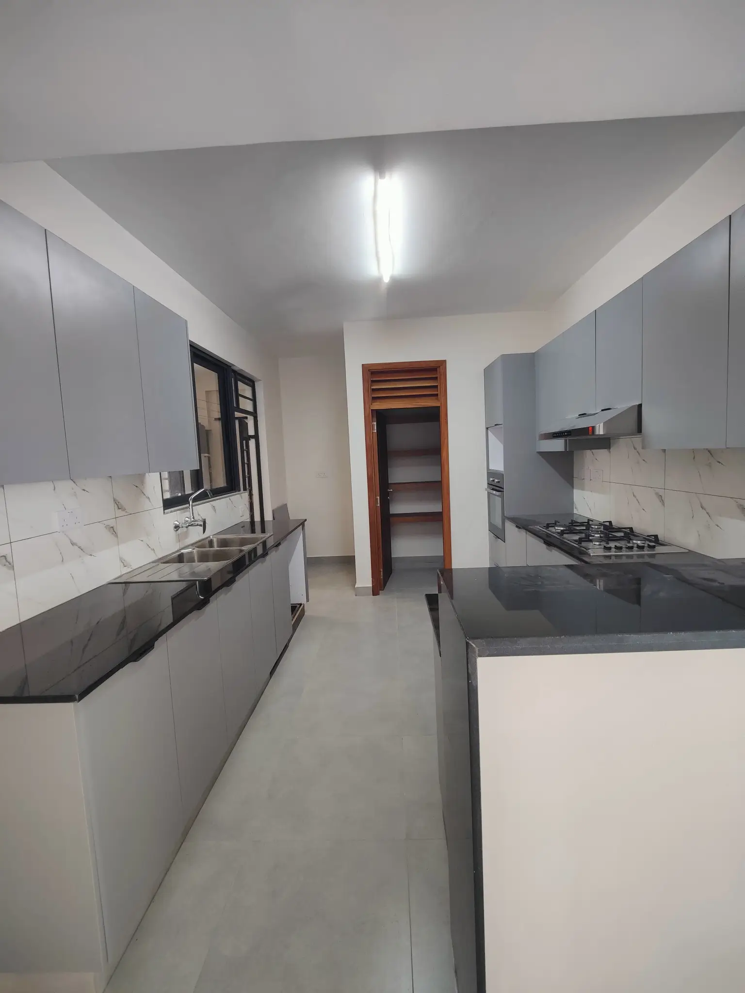 Modern galley kitchen with gray cabinetry and marble backsplash