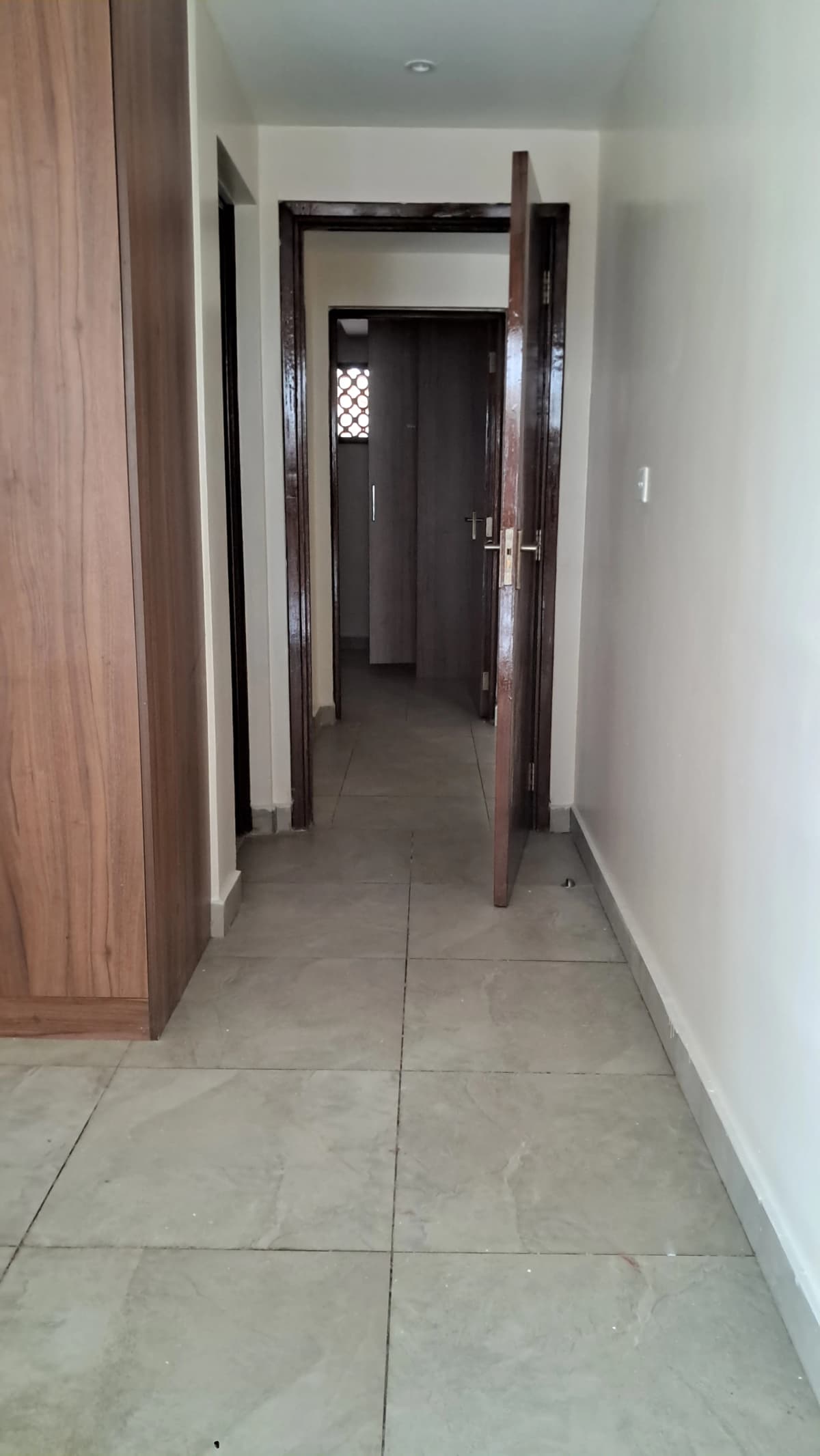 Internal hallway with tiled flooring and dark wooden doors