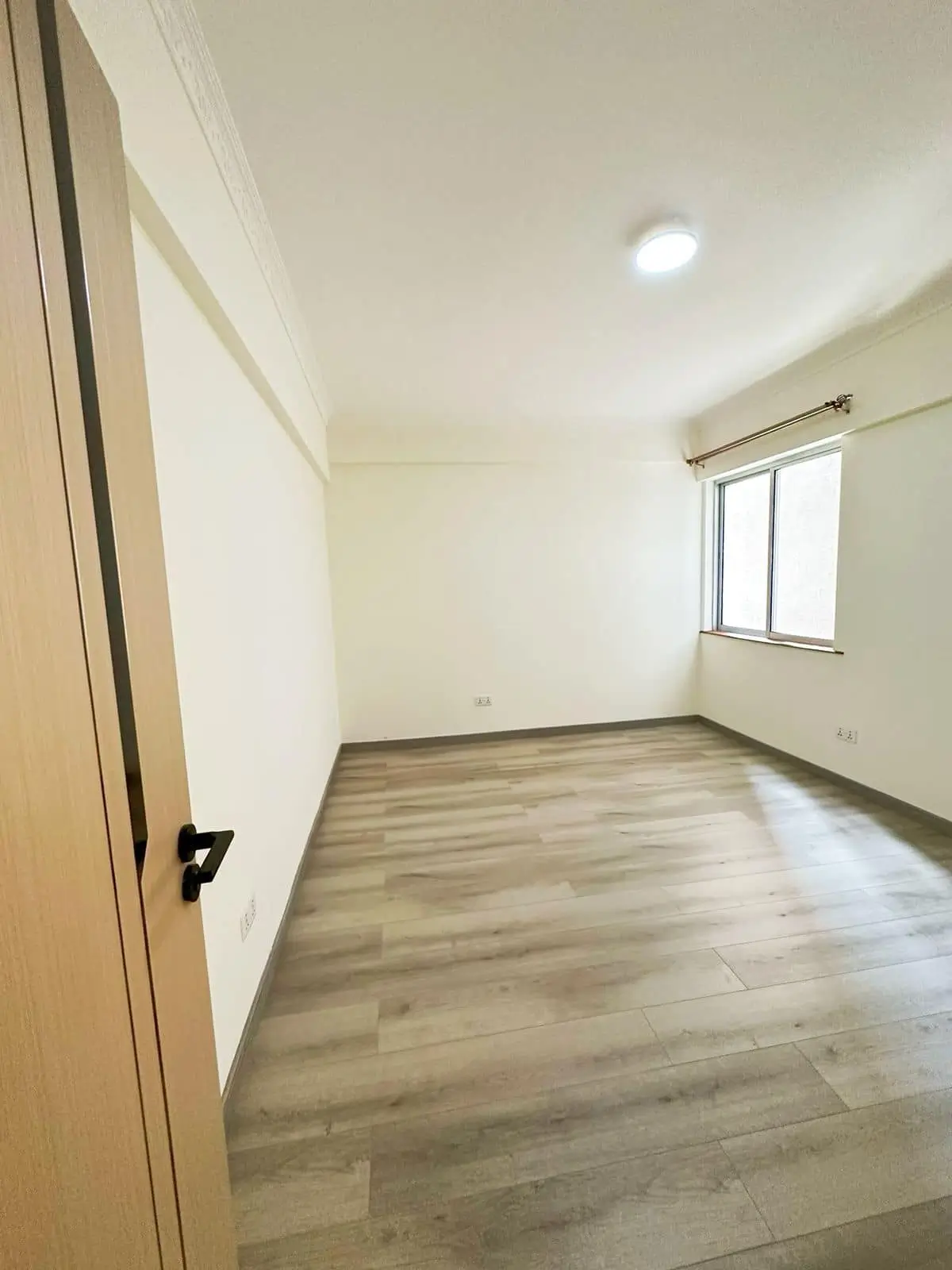 Empty bedroom with wooden flooring and natural light