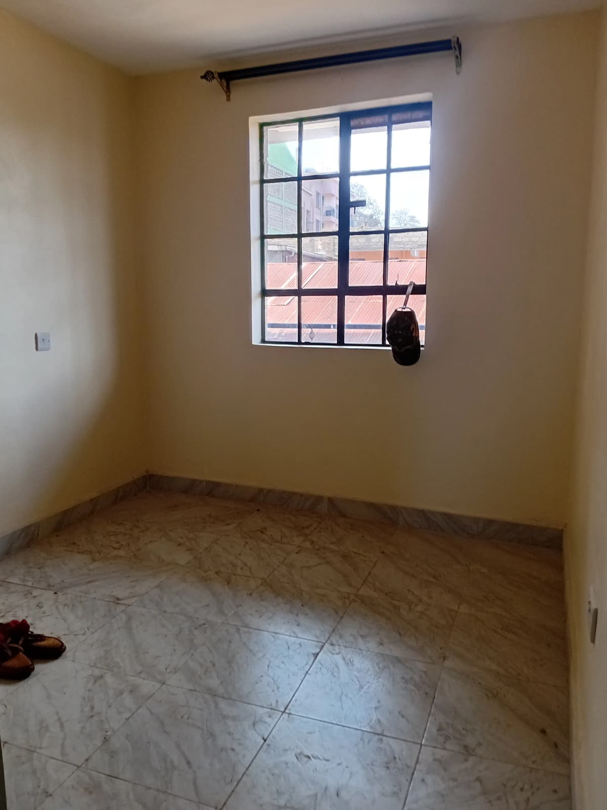 Empty bedroom with large window and tiled flooring