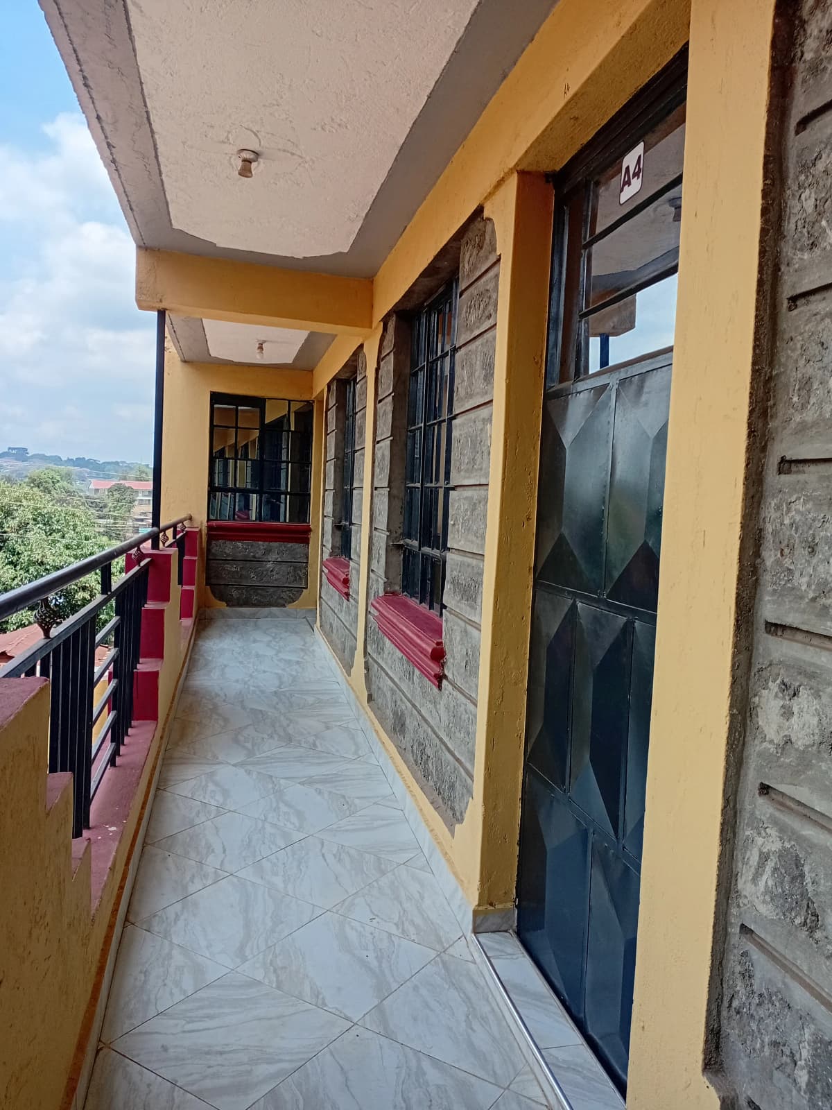 Yellow-painted balcony with red railings and scenic valley views
