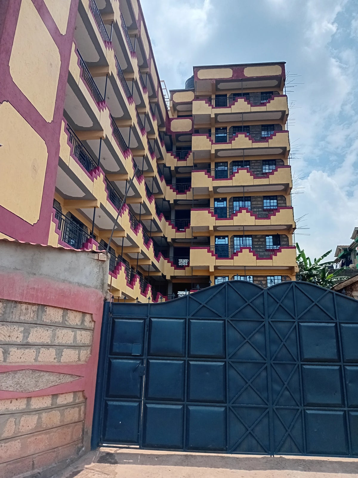 Multi-story residential building facade with blue metal gate entrance