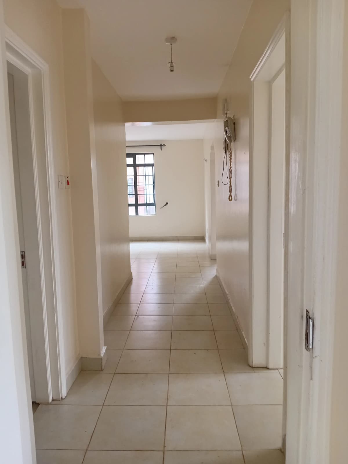 Bright neutral hallway with tiled flooring and white doors