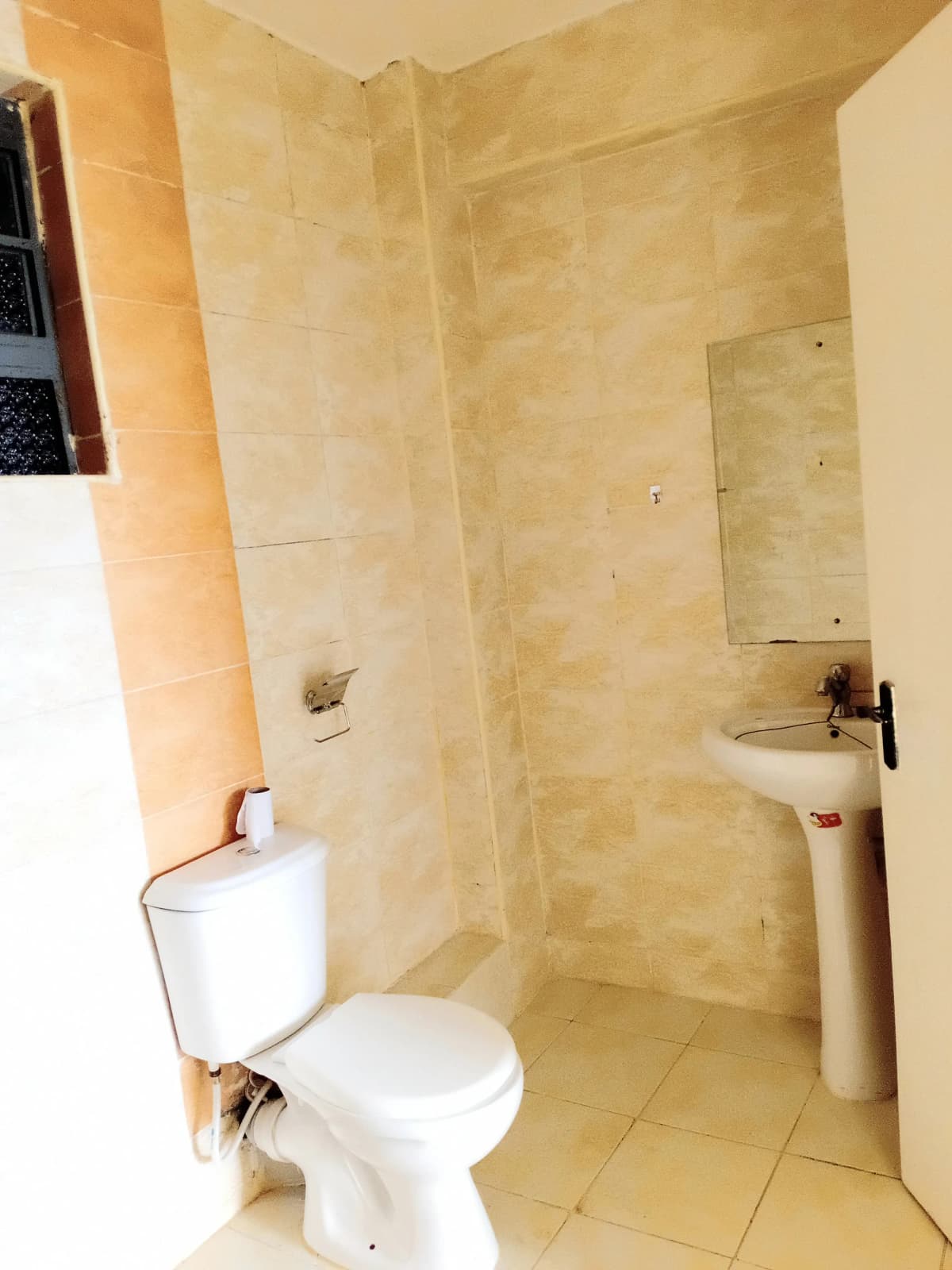 Compact bathroom with toilet, pedestal sink, and tiled shower area