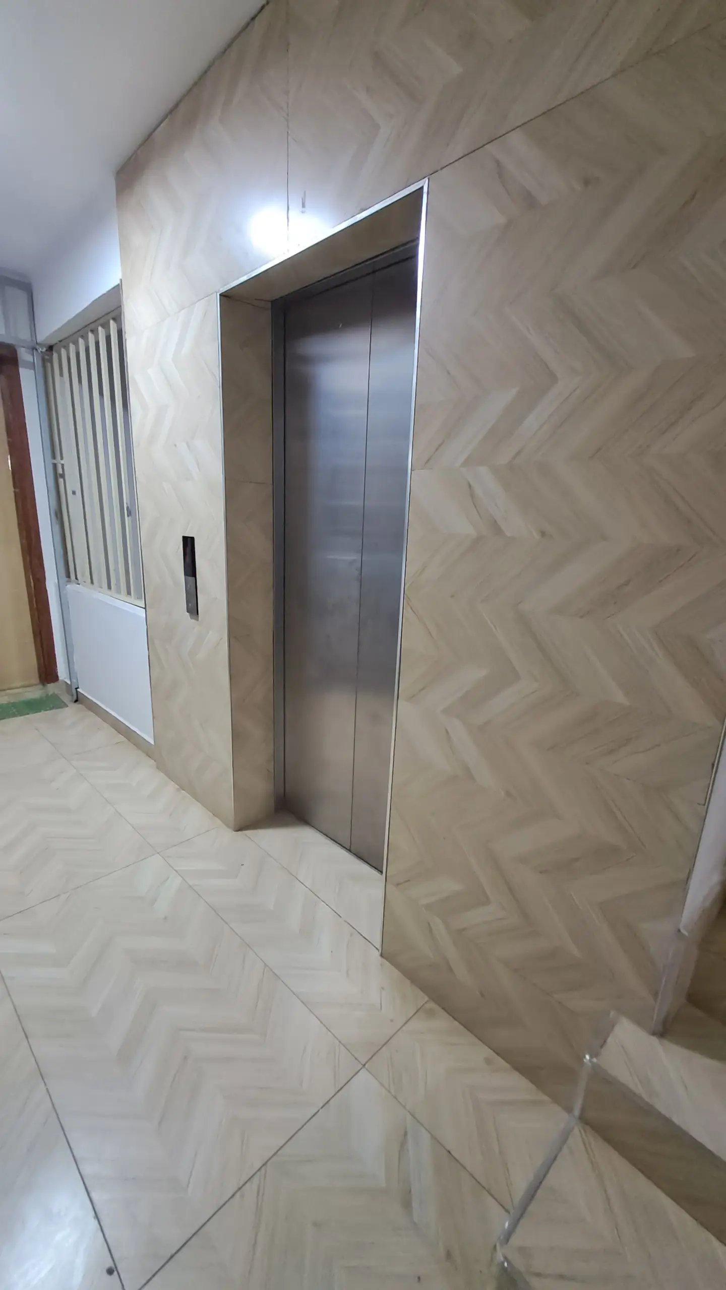 Modern elevator lobby with geometric wall paneling and polished flooring