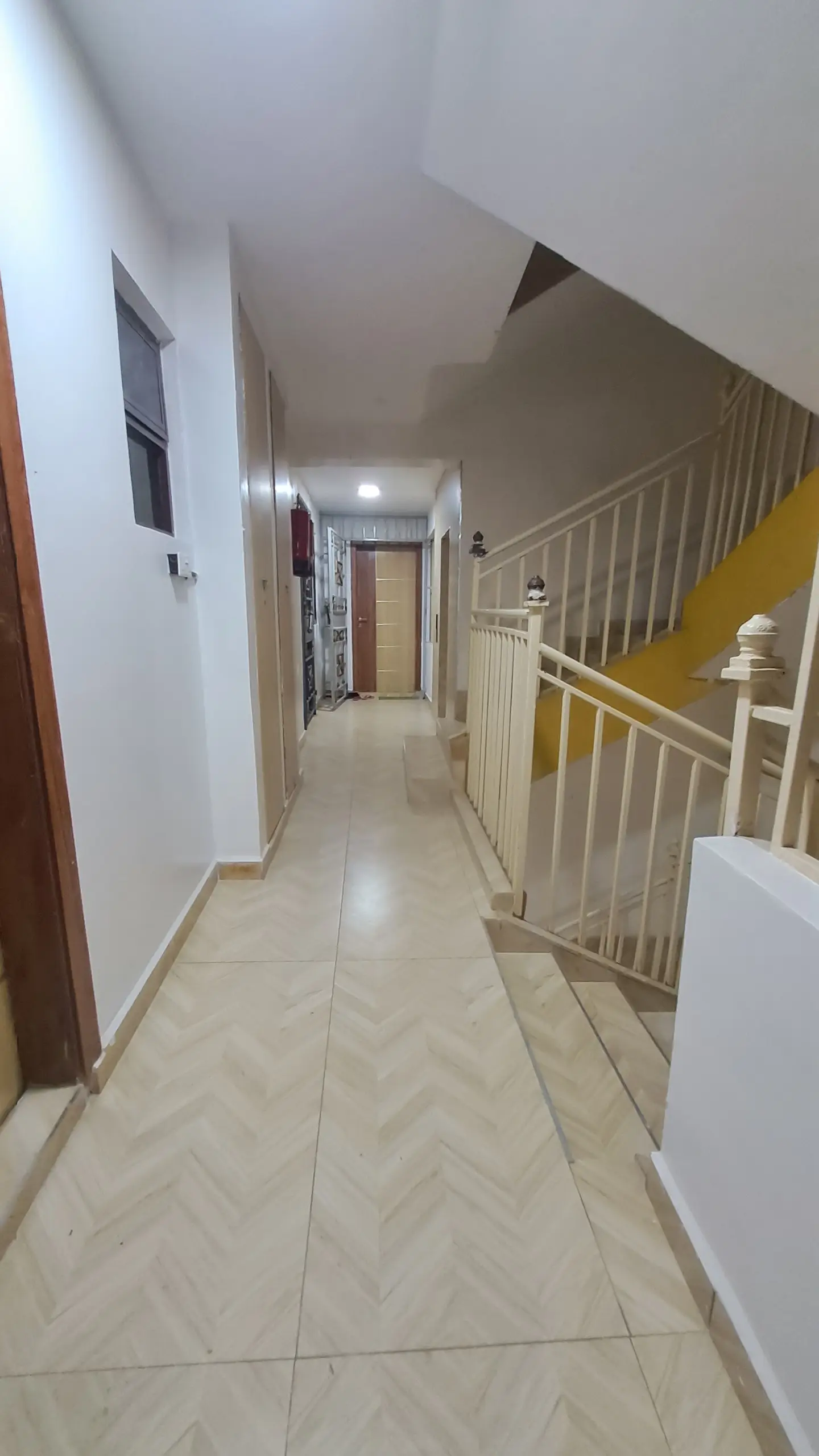 Bright corridor with staircase and neutral tile flooring