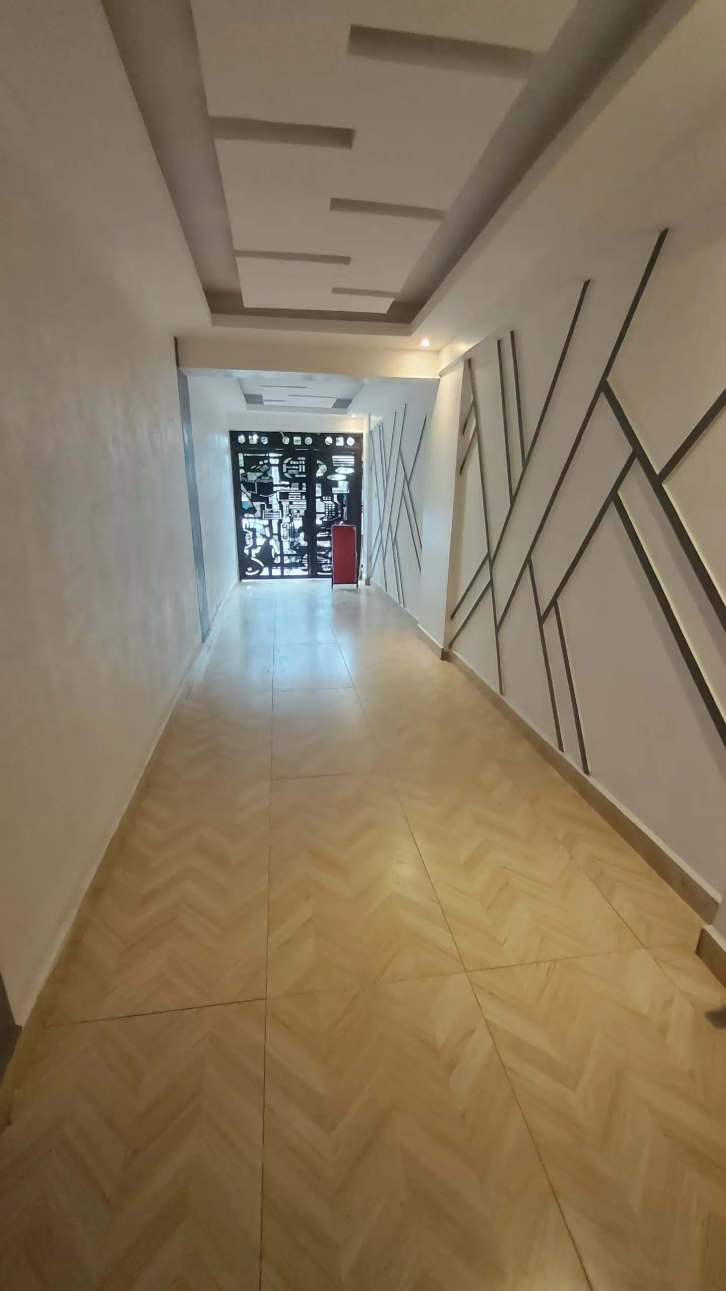 Modern corridor with coffered ceiling and polished tile flooring